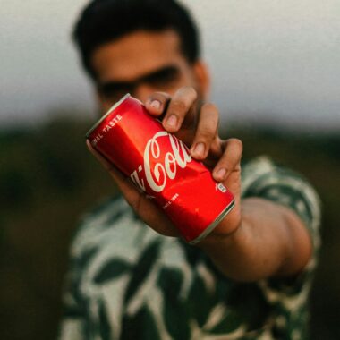 Selective Focus Photo of a Man's Hand Holding a Soda Can